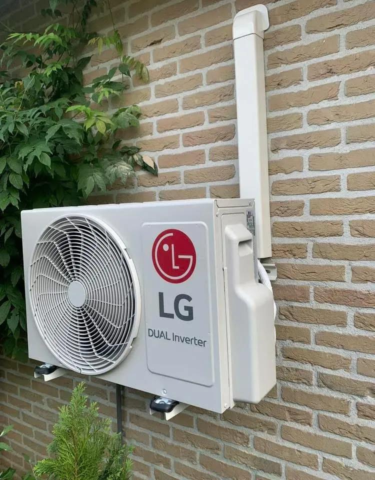 LG-buitenunit aan een bakstenen gevel met witte leidinggoot